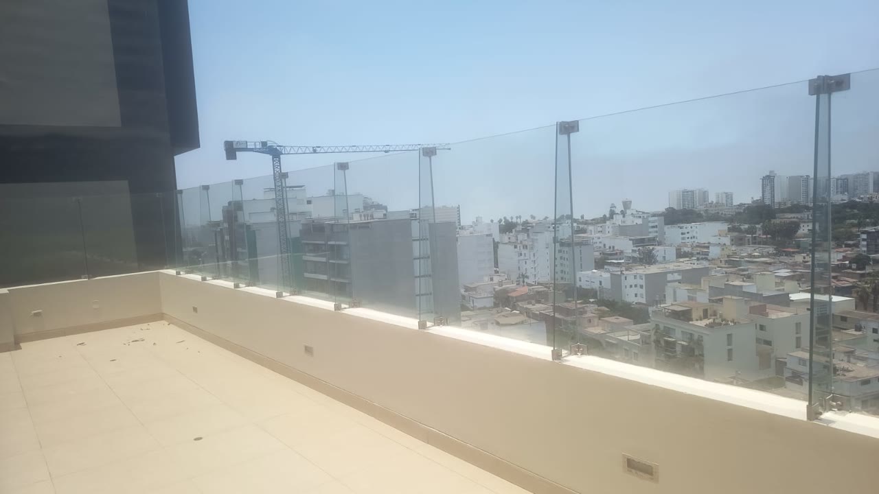 Terraza elevada con baranda de vidrio y vista de la ciudad.
