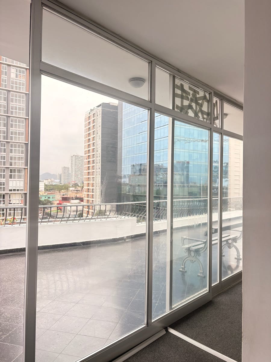 Paneles de vidrio instalados en un ambiente alto con vista a edificios de Lima.