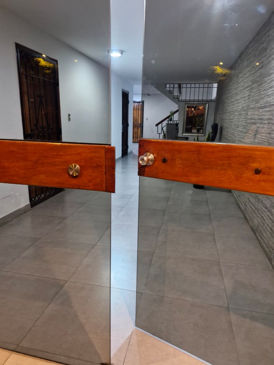 Vista interior de un acceso de vidrio con tiradores y franja de seguridad.