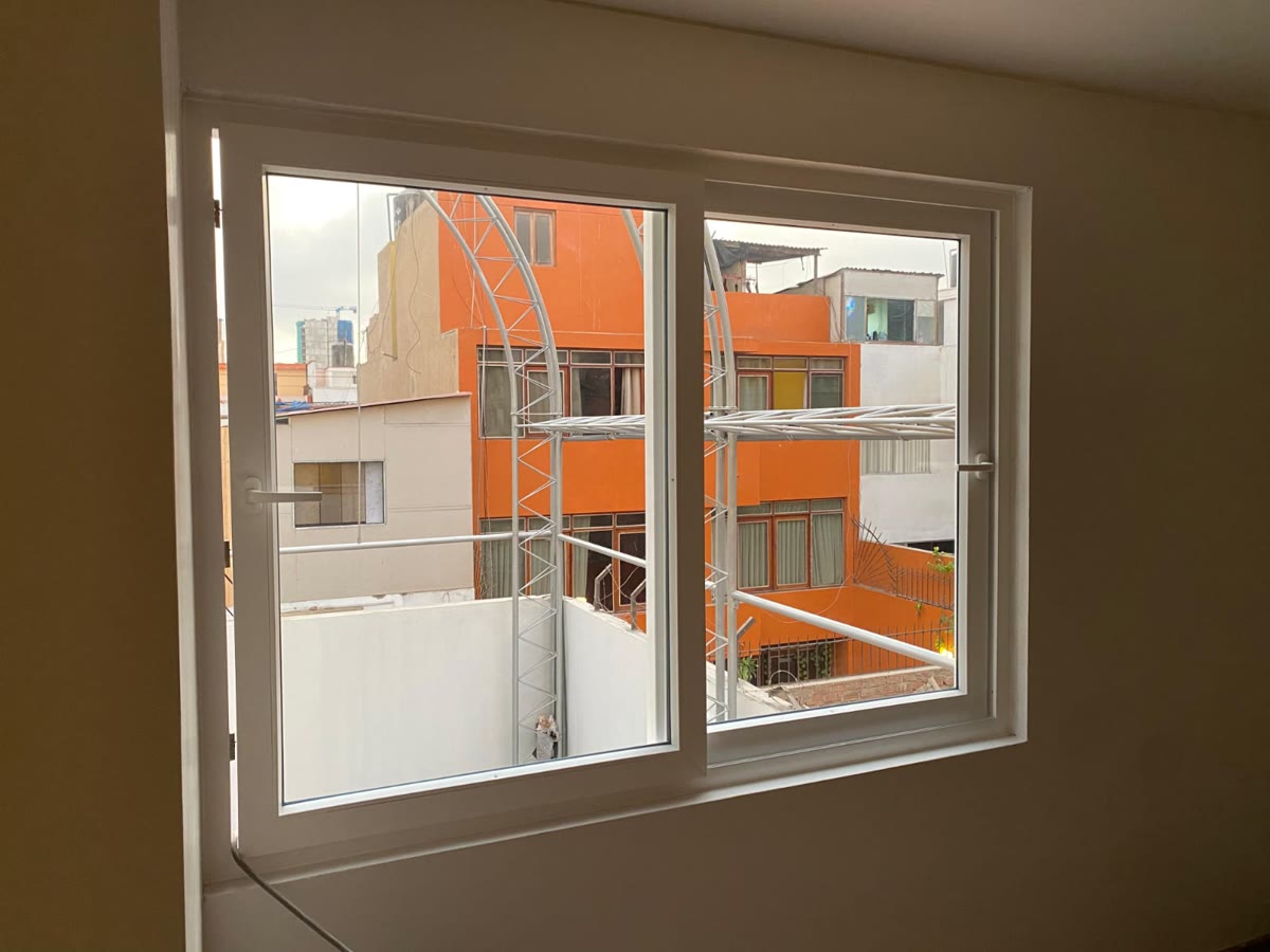 Ventana blanca de dos hojas vista desde el interior de una habitación.